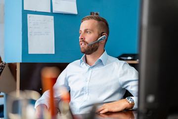Businessman with headset at desk in office