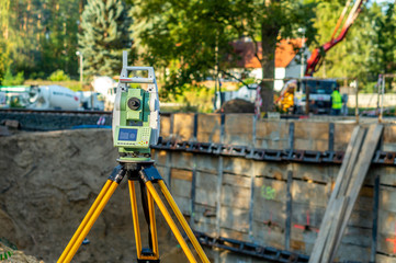 Surveyor equipment (theodolite) on construction site of the airport, building or road with construction machines in background