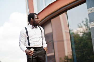 Handsome fashionable african american man in formal wear, bow tie and suspenders, walking stick.