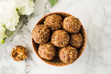 Energy protein balls with healthy ingredients on marble table. Home made with dates, peanut butter, flax and chia seeds, oats, almond and chocolate drops © tenkende