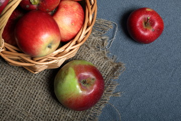 Wicker basket with ripe juicy apples. Nearby are a few apples. New crop. On a gray background. View from above.