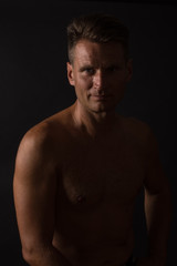 Fototapeta premium Bust of mature man who poses in split light on black background