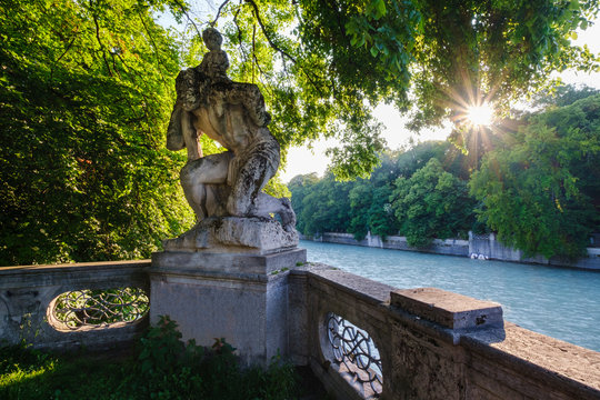 Germany, Upper Bavaria, Munich, St. Christopher's statue surrounded with trees by Isar river at sunset