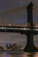 Fototapeta premium Manhattan Bridge from the East river at night with moon in a crescent phase