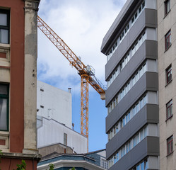 Remote control tower crane working between buildings in Coruna Spain