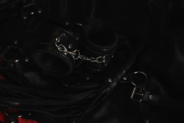 A variety of sex toys (whip, handcuffs, anal plug and others) are on a dark background. Image for...