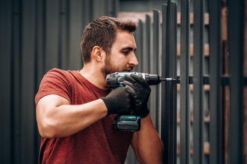 construction worker using electric screwdriver and drilling holes in metal surface