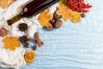 A bottle of mulled wine with spices, scarf, dry leaves and oranges on a table. Autumn mood, a...