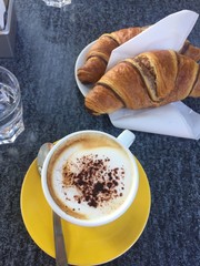 cup of coffee and croissant on wooden table