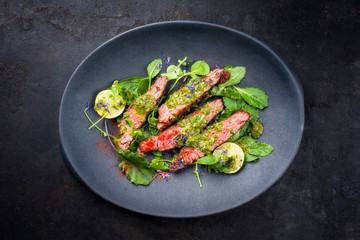 Barbecue Wagyu Bavette Steak mit Chili, Salat und Chimichurri Sauce als Draufsicht auf einem Modern Design Teller mit Textfreiraum