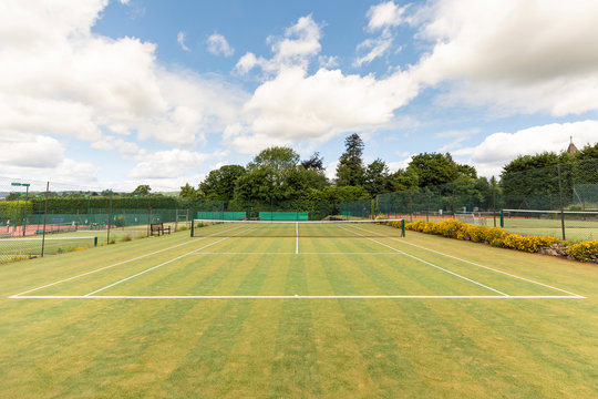 Sports net and single line markings in empty tennis court against sky