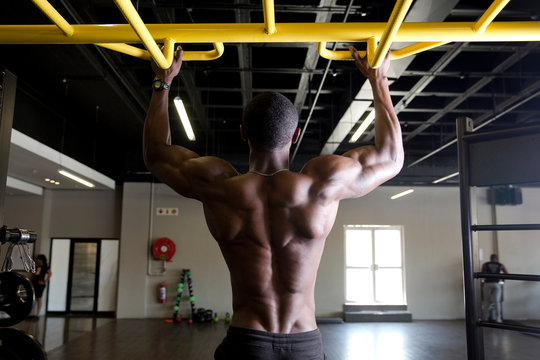 African man training on bar in gym