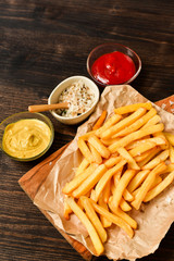 French fries with ketchup, mustard and salt. fast food lunch on a wooden table. Business lunch menu, fast food delivery, selective focus and copy space