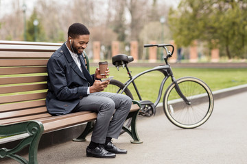 Coffee break. Happy businessman using phone next to bike