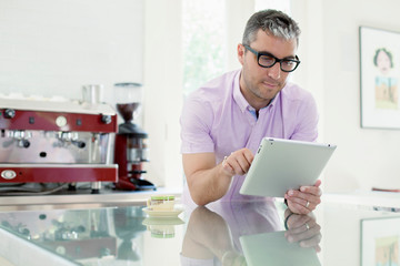Young white man working on his iPad in the kitchen