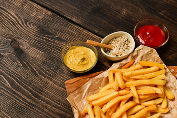 French fries with ketchup, mustard and salt. fast food lunch on a wooden table. Business lunch menu, fast food delivery, selective focus and copy space