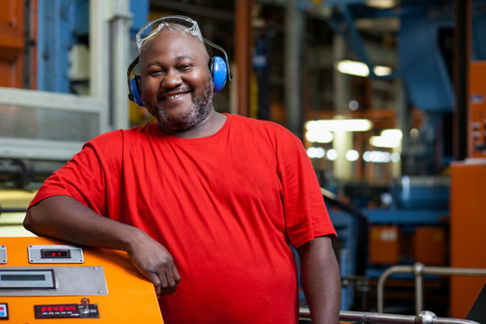 African man standing next to a machine at a warehouse