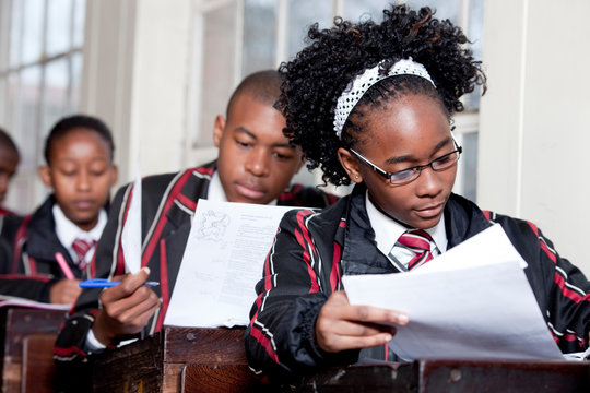 A Female teenage student writing a test in a classroom
