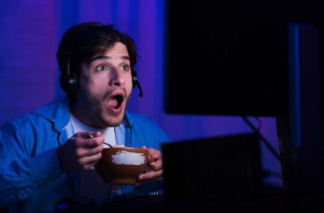 Shocked man eating and playing online games at home