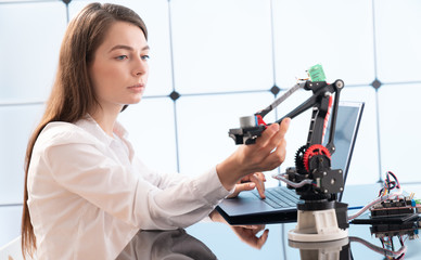A young woman writes an algorithm for the robot arm. Science Research Laboratory for Robotic Arm Model. Computer Laboratory