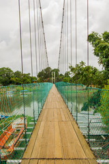 Obraz premium hanging wood floor bridge across the river with a cloudy sky