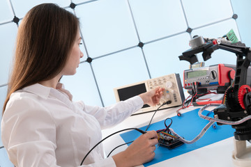 A young woman writes an algorithm for the robot arm. Science Research Laboratory for Robotic Arm Model. Computer Laboratory