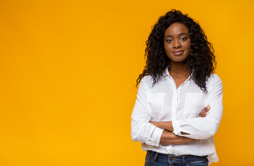 Confident young african woman posing on yellow studio background