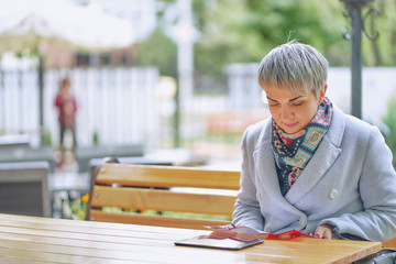 short-haired business woman in a white coat in a street cafe