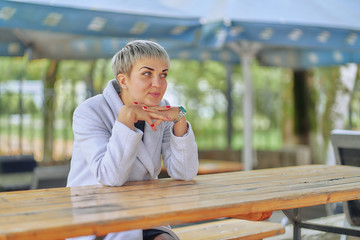 short-haired business woman in a white coat in a street cafe