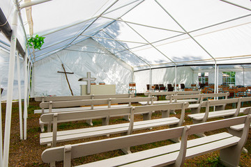 Pulpit, cross and benches at a tent revival.