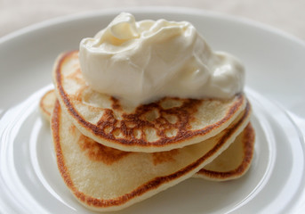 Fresh hot flapjack pancakes stack on white plate on natural light linen tablecloth background. Soft focus. Copy space. Pancake carnival maslenitsa breakfast concept