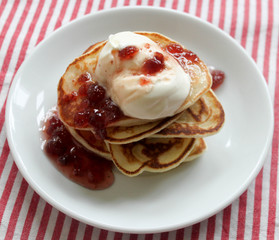 Fresh hot pancakes stack with strawberry jam and sour cream on white plate on natural light linen tablecloth background. Soft focus. Copy space. Pancake carnival maslenitsa breakfast concept
