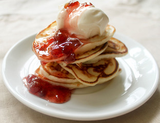 Fresh hot pancakes stack with strawberry jam and sour cream on white plate on natural light linen tablecloth background. Soft focus. Copy space. Pancake carnival maslenitsa breakfast concept