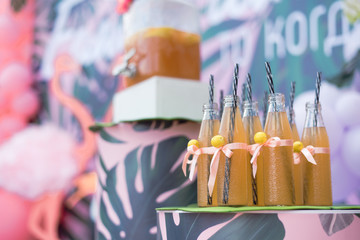 Homemade Lemon Lemonade at the birthday party. Juice in a glass jug with a tap and bottles with straws