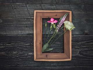 Flowers in wooden frame on dark background. Overhead shot.