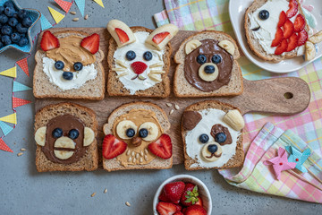Funny animal faces toasts with spreads, butters, banana, strawberry and blueberry