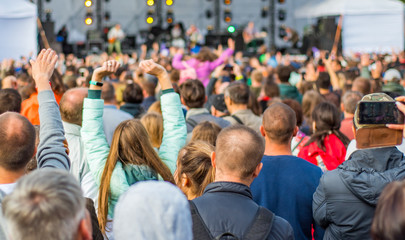 many different people at a concert listening to rock band music open air