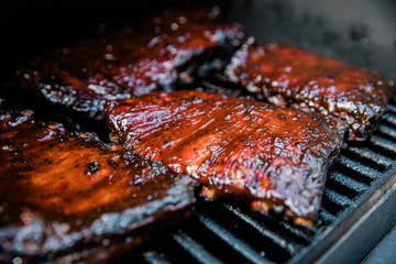 Smoked Barbecue BBQ ribs on the smoker grill charred on the edges and covered in barbecue sauce homemade