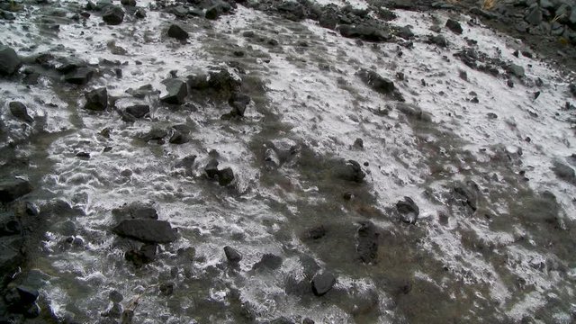 High angle, water flows under sheet of ice