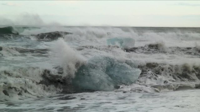 Medium shot, waves crash over glacial ice in Iceland