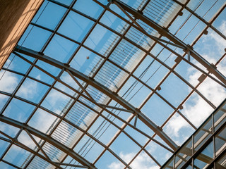 Openwork glazing of the roof over the shopping center. Ceiling in the form of a steel arch with glass windows. Blue sky on a cloudy day