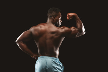 Fototapeta na wymiar Hot bodybuilder demonstrating his biceps over black background