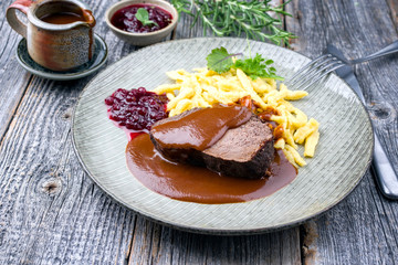 Traditional braised marinated German Sauerbraten from beef with spaetzle and cranberry jam in spicy...