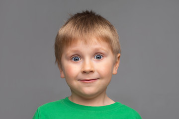 Portrait of happy smiling boy in green t-shirt. Attractive kid in studio. Childhood concept.