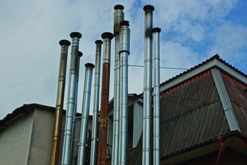 a row of gray metal long pipes on the wall of a building against the sky