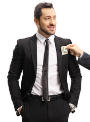 Male hand putting money in a businessman's suit pocket