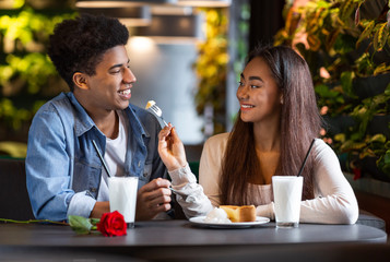 Pretty teen girl feeding her boyfriend at cafe