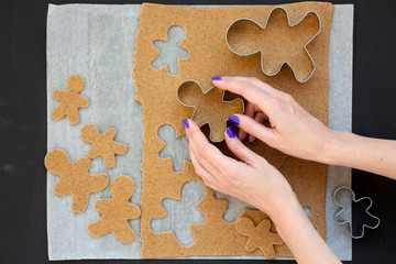 Woman making Christmas cookies on a black background, top view. From above, overhead.