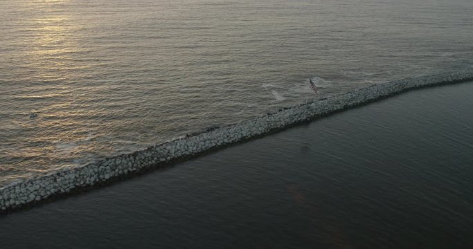 Helicopter aerial shot of American flag flying in ocean, sunset