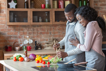 Cheerful black family cooking dinner together in kitchen